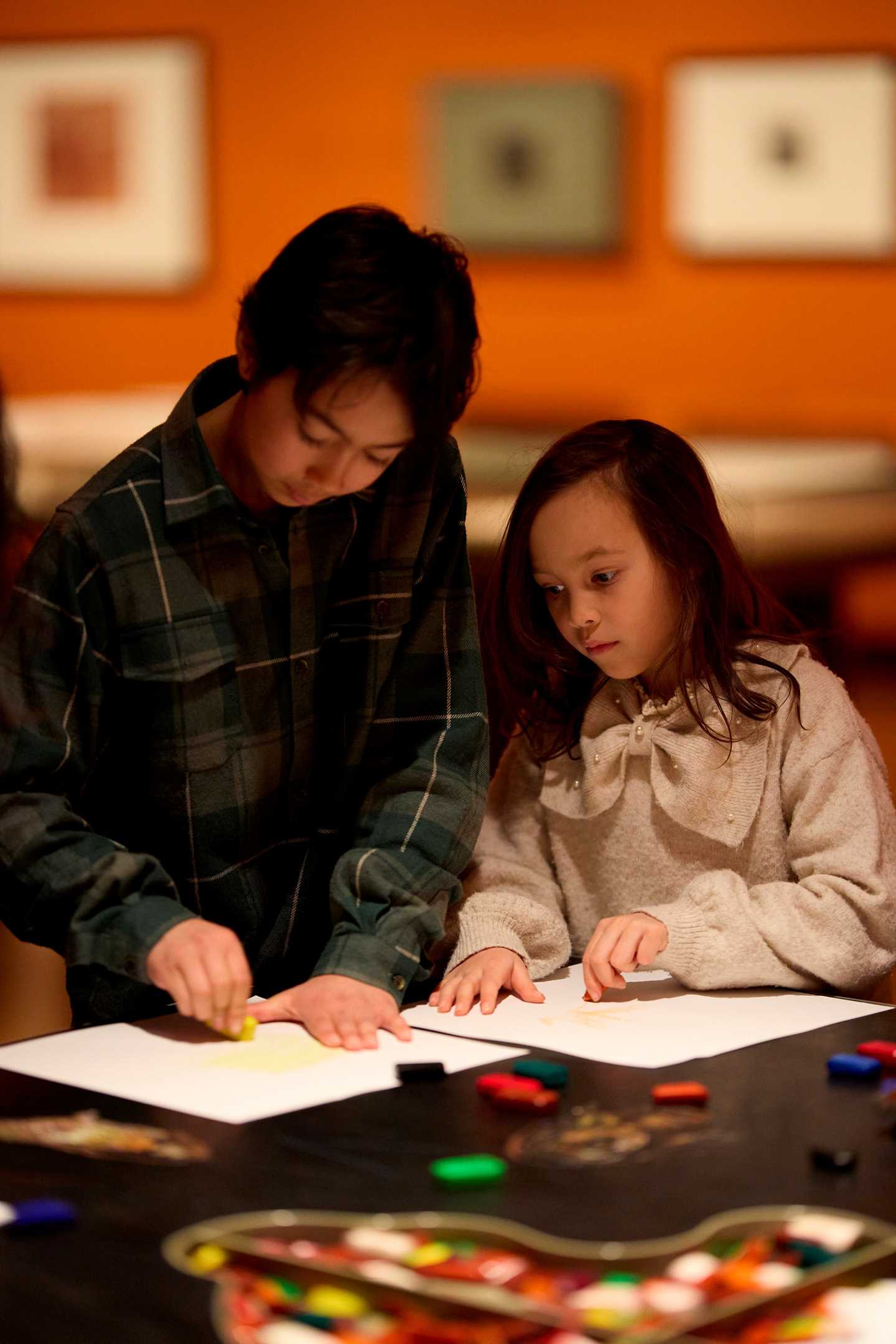Two children drawing at a table in the Inntil exhibition. Photograph.