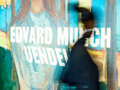 A person walking past the sign at the entrance to the Infinity exhibition at MUNCH. Photograph.