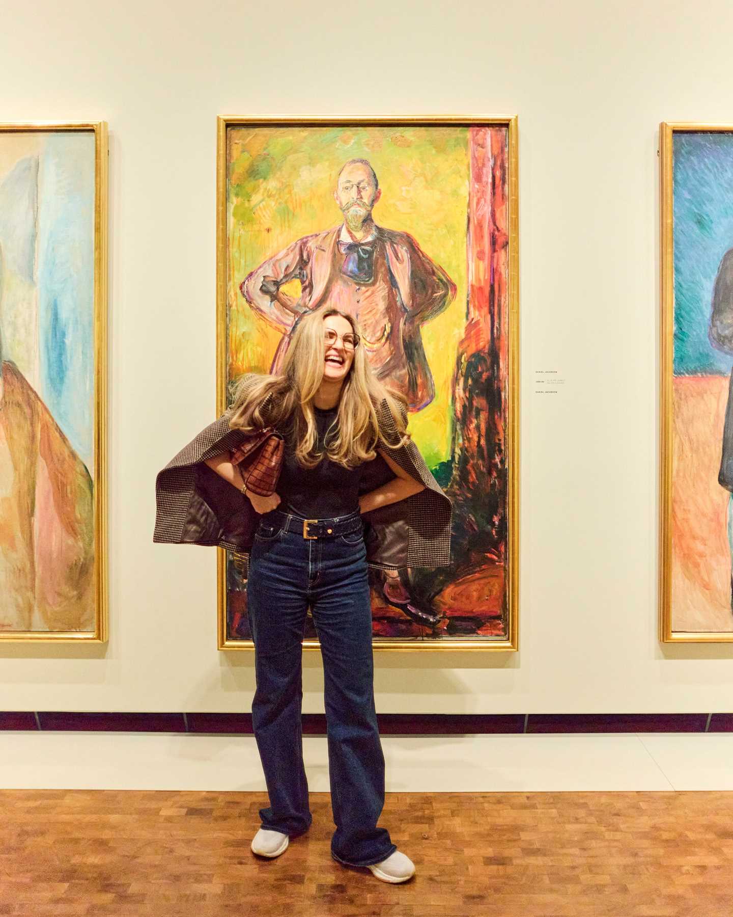 Woman laughing while posing in front of a Munch painting. Photograph