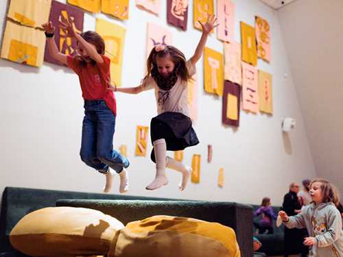Kids playing in The Chamber of Chaos, a wonderful world of portals, colourful pillows and textile figures, surrounded by magical lighting