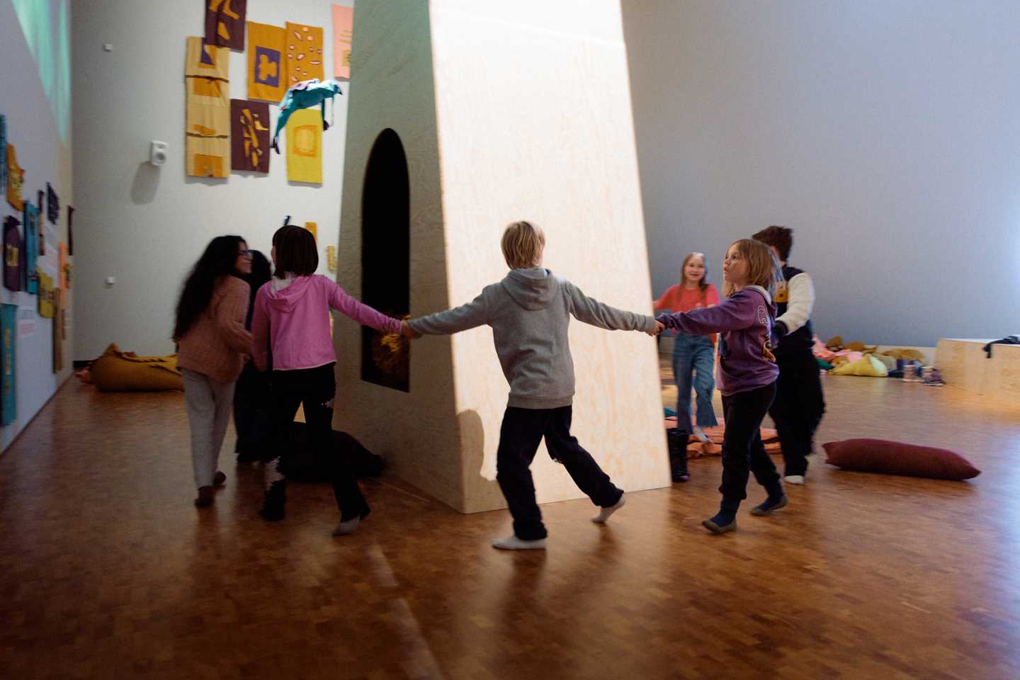 Kids playing in The Chamber of Chaos, a wonderful world of portals, colourful pillows and textile figures, surrounded by magical lighting