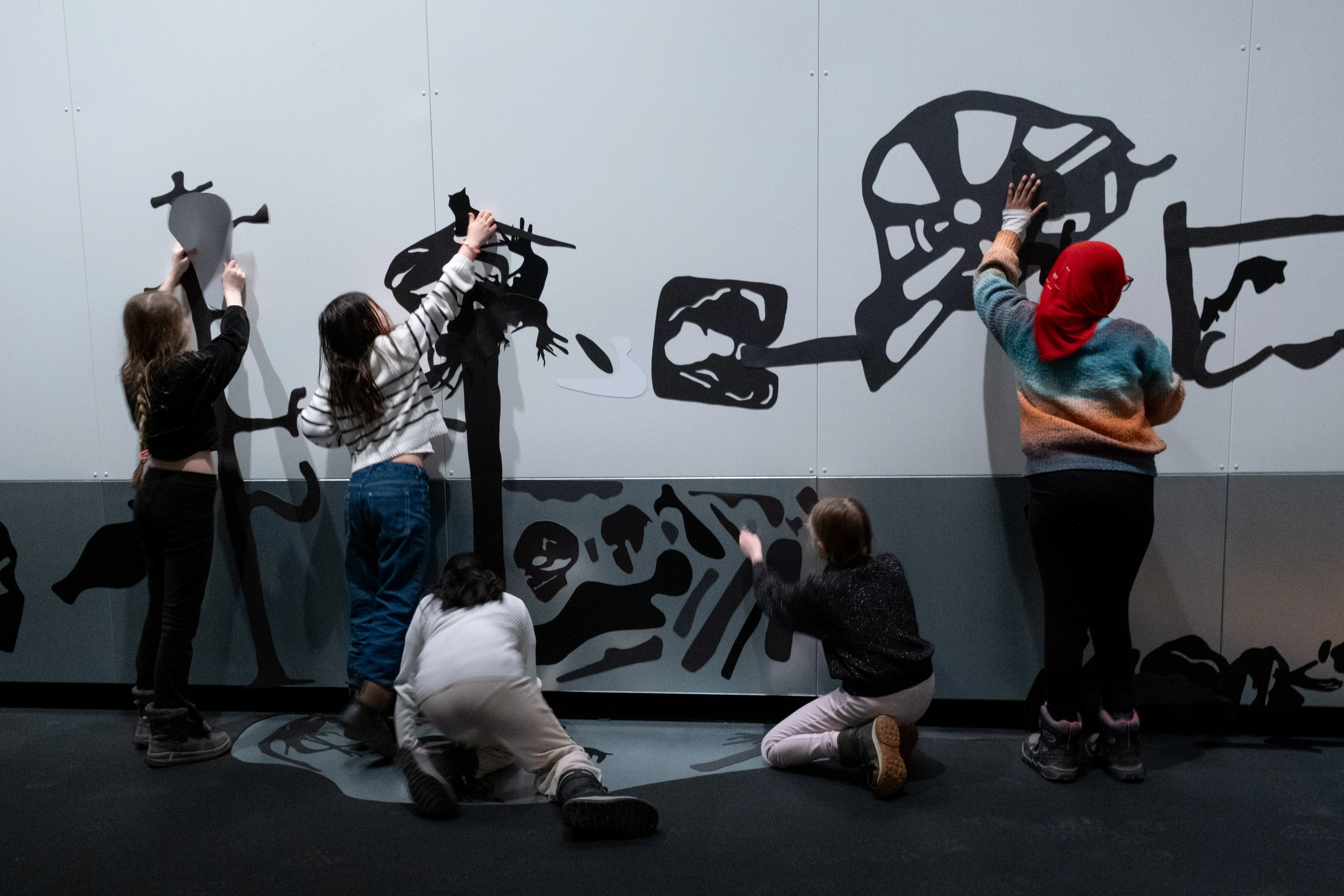 Five children putting magnets on the wall in the exhibition