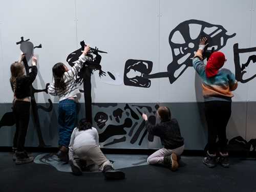 Five children putting magnets on the wall in the exhibition