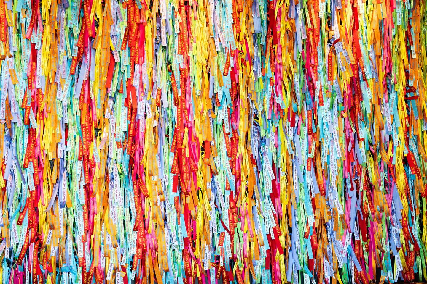 Densely hung colourful Brazilian ribbons at the entrance to the exhibition. Photograph.