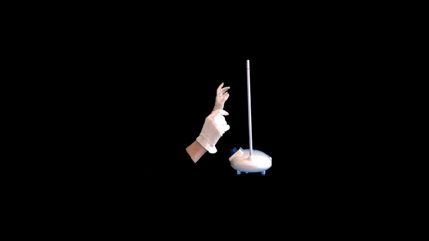 On a black background, two animated hands in white gloves are shown in profile, appearing to conduct something. Screenshot.