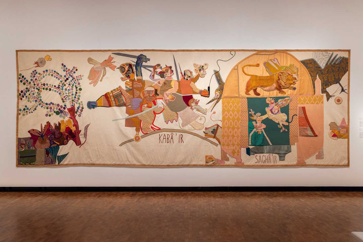 A large textile work by Paula Rego covers an entire wall in an exhibition gallery. Photograph.
