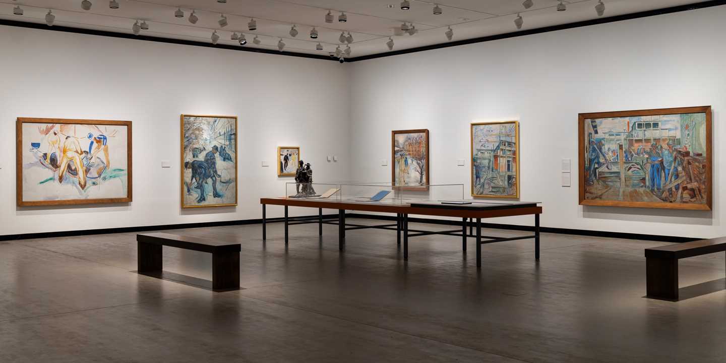 Overview of an exhibition gallery showing several paintings with worker motifs by Edvard Munch. Photograph.