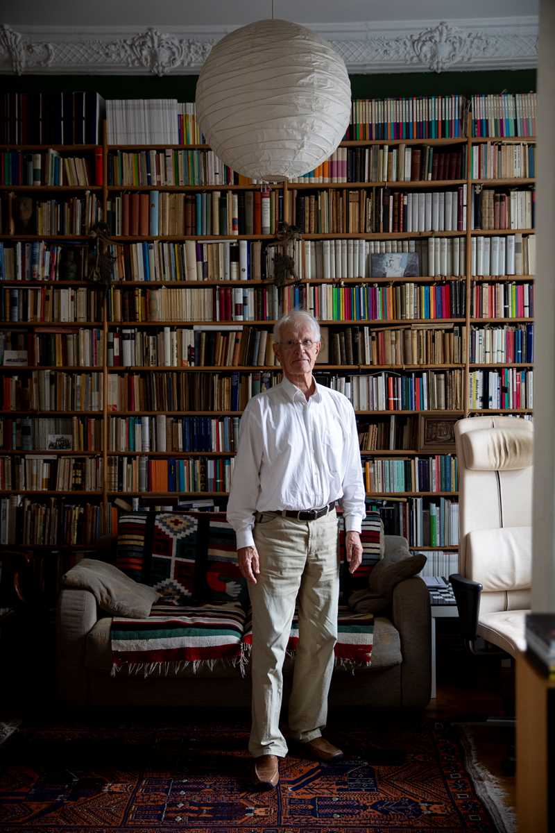 Foto av Jan Brockmann stående i et rom fylt med bøker.
