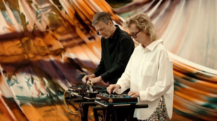 Photo of a man and a woman playing a synth concert in an exhibition space. 